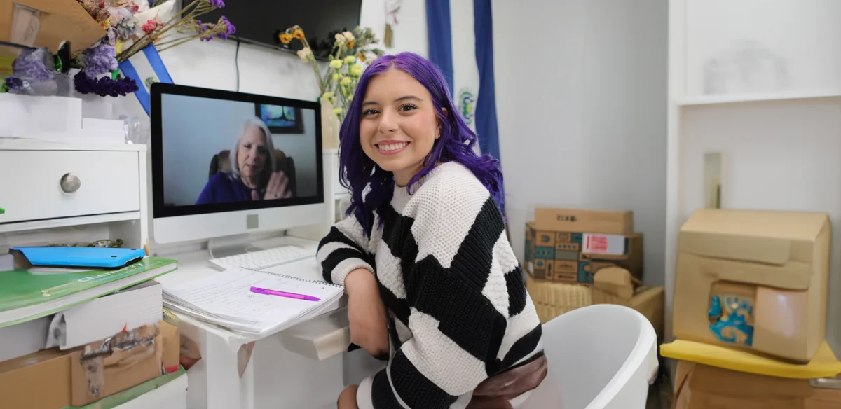 Estudiante de bachillerato asistiendo a una clase online en casa con un jersey de rayas